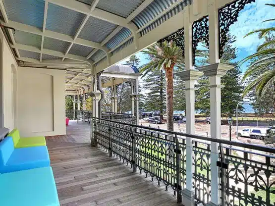 Brighton Prep School verandah with ocean view, palm trees, and decorative ironwork railing.